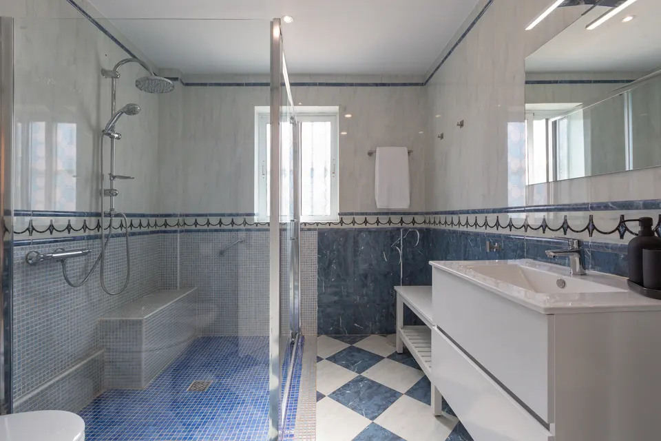 Baño principal con ducha y revestimiento azul